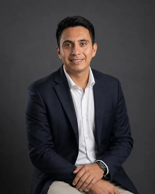Denis Siavichay, in a navy blazer and a white shirt, smiling at the camera.